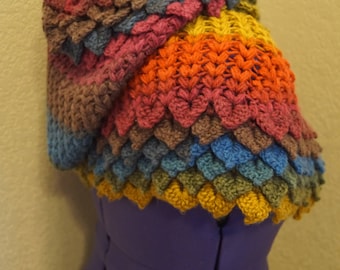 May include: A colorful crocheted shawl with a scalloped edge. The shawl is made in a variety of shades of brown, red, orange, yellow, blue, and green.