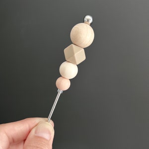 May include: A wooden bead necklace with a silver top and a mix of beige, light pink, and white beads.