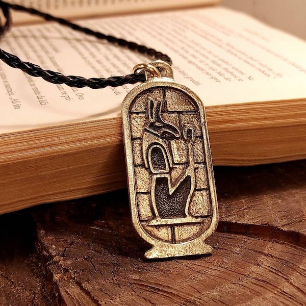 Ancient Egyptian god Seth golden bronze cartouche pendant , lord of chaos magical artefact , dark entity deity depiction , Setekh hieroglyph