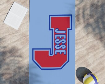 May include: A blue beach towel with a large red letter J with a blue outline. The name "Jesse" is written inside the letter in a white cursive font.