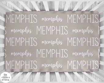 Può includere: Un lenzuolo per lettino grigio con la parola "Memphis" ripetuta in bianco.