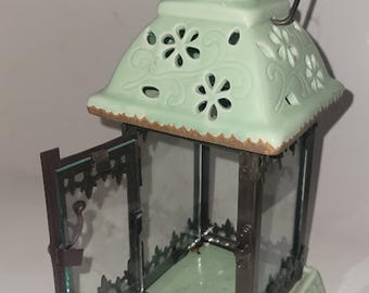 Farol portavelas de cerámica verde menta con forma de pájaro y asa de alambre. Decoración rústica.