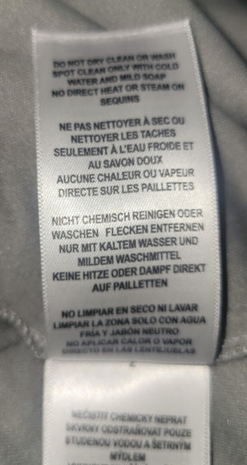 Puede incluir: Etiqueta de tela blanca con instrucciones de cuidado en ingl&eacute;s, franc&eacute;s, alem&aacute;n, espa&ntilde;ol y checo. La etiqueta desaconseja la limpieza en seco y el lavado, y recomienda limpiar las manchas con agua fr&iacute;a.