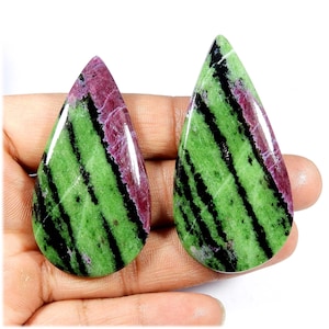 Può includere: Due pietre preziose a forma di goccia. Le pietre presentano un colore di base verde vibrante con strisce diagonali nere e una sezione rosso-viola scuro nella parte superiore. Le pietre lucide hanno una finitura lucida.