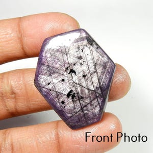 Op de afbeelding: Een gefacetteerde, paarse edelsteen met een unieke, onregelmatige vorm. De steen heeft een netwerk van donkere, lineaire insluitsels en een gepolijst oppervlak. De tekst "Front Photo" is zichtbaar onderaan de afbeelding.