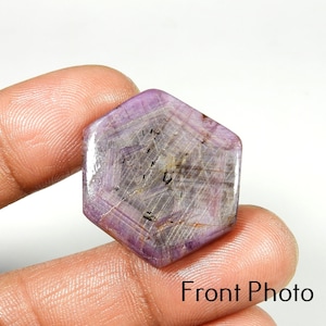 Op de afbeelding: Een zeshoekige, gepolijste edelsteen met een lichtpaarse tint. De steen is doorschijnend, met zichtbare interne lijnen en insluitsels. De tekst "Front Photo" is rechtsonder zichtbaar.