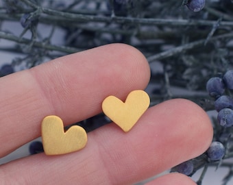 May include: A pair of gold heart-shaped earrings. The earrings are small and delicate, and they are perfect for everyday wear.