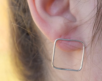 May include: A pair of silver square earrings. The earrings are simple and modern, and they would be a great addition to any jewelry collection.
