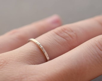 May include: A thin, silver band ring with a textured surface.