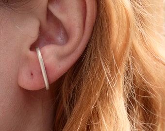 Può includere: Un orecchino a cerchio d'argento indossato nella parte superiore dell'orecchio.