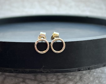 May include: A pair of small, gold-toned circle earrings with a hammered texture.