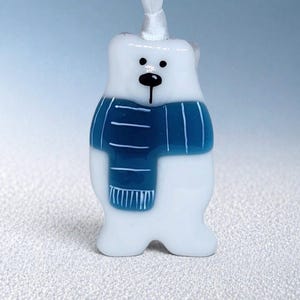 Peut inclure: Ornement en forme d'ours polaire blanc avec une écharpe bleue. L'ours a un nez et des yeux noirs. Un ruban blanc est attaché en haut pour l'accrocher. Décoration mignonne sur le thème de l'hiver.