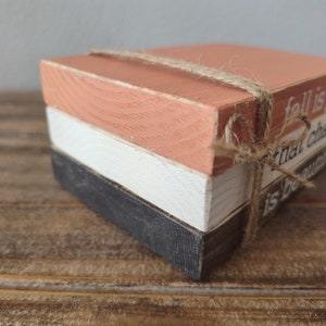 Puede incluir: Tres bloques de madera apilados uno encima del otro, atados con un cordel. El bloque superior est&aacute; pintado de color naranja claro y tiene el texto "fall is proof that change is beautiful" escrito en &eacute;l.