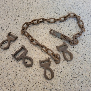 May include: A set of five rusty metal clasps and a chain. The clasps are various shapes and sizes, and the chain is made of linked metal rings.