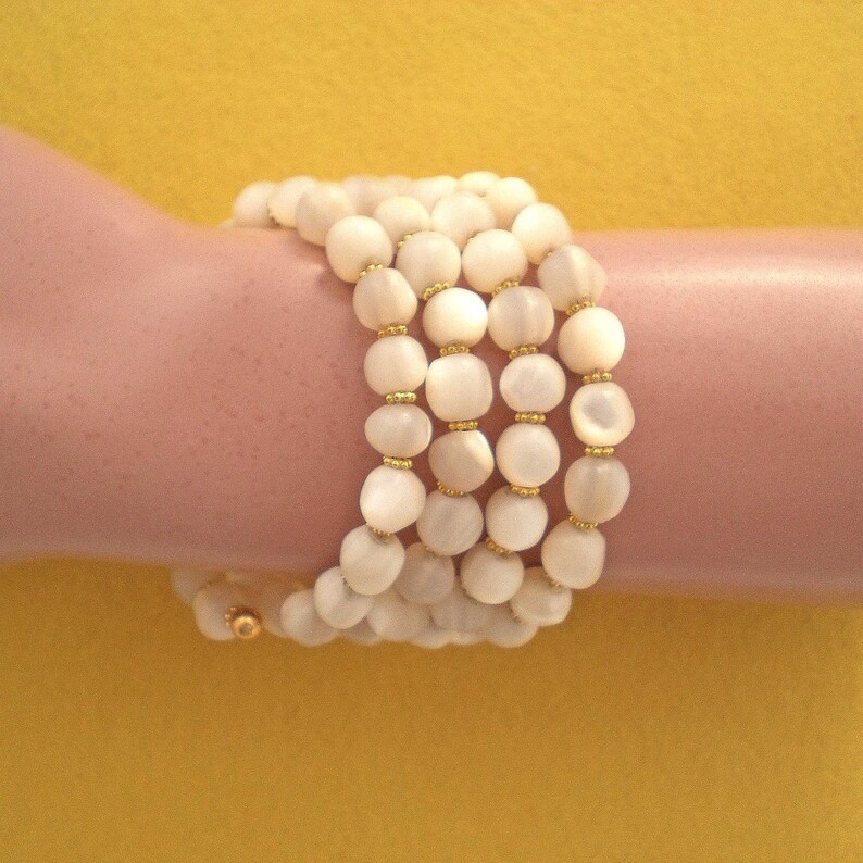 This unique handmade memory wire bracelet has more than 90 white mother of pearl beads interspersed with tiny gold plated spacer beads.  It is finished with gold plated end caps. It will fit any size of wrist, with four to five circles in total.