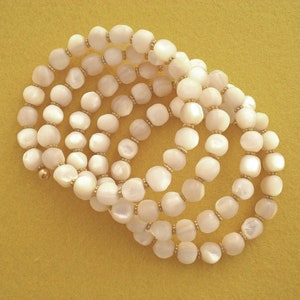 This unique handmade memory wire bracelet has more than 90 white mother of pearl beads interspersed with tiny gold plated spacer beads.  It is finished with gold plated end caps. It will fit any size of wrist, with four to five circles in total.