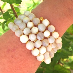 This unique handmade memory wire bracelet has more than 90 white mother of pearl beads interspersed with tiny gold plated spacer beads.  It is finished with gold plated end caps. It will fit any size of wrist, with four to five circles in total.