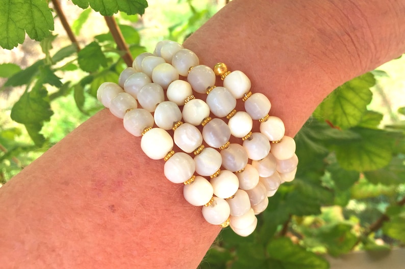 This unique handmade memory wire bracelet has more than 90 white mother of pearl beads interspersed with tiny gold plated spacer beads.  It is finished with gold plated end caps. It will fit any size of wrist, with four to five circles in total.