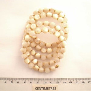 This unique handmade memory wire bracelet has more than 90 white mother of pearl beads interspersed with tiny gold plated spacer beads.  It is finished with gold plated end caps. It will fit any size of wrist, with four to five circles in total.