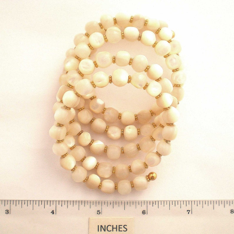 This unique handmade memory wire bracelet has more than 90 white mother of pearl beads interspersed with tiny gold plated spacer beads.  It is finished with gold plated end caps. It will fit any size of wrist, with four to five circles in total.
