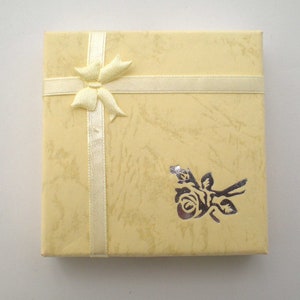 Bracelet will be sent in a 3.5in (9cm) square pale yellw ribboned gift box with a silver rose motif.