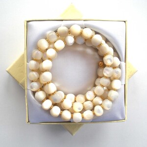 This unique handmade memory wire bracelet has more than 90 white mother of pearl beads interspersed with tiny gold plated spacer beads.  It is finished with gold plated end caps. It will fit any size of wrist, with four to five circles in total.