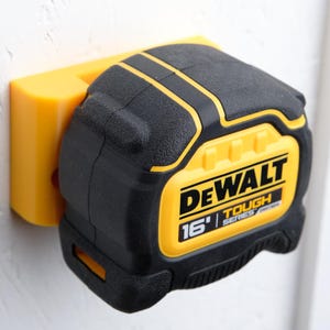 May include: A yellow and black DeWalt 16' Tough Series tape measure mounted on a yellow wall mount.