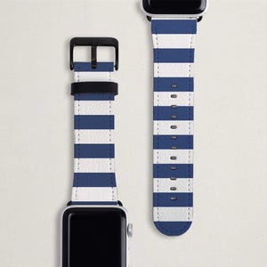 May include: Two Apple Watch straps with a white and navy blue striped design. One strap is attached to a silver watch face, and the other is detached. The straps have a leather-like texture and a black buckle.