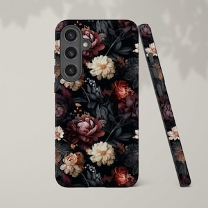 May include: A black phone case with a floral pattern. The flowers are in shades of red, pink, and white, and the background is black. The case has a cutout for the camera lens.