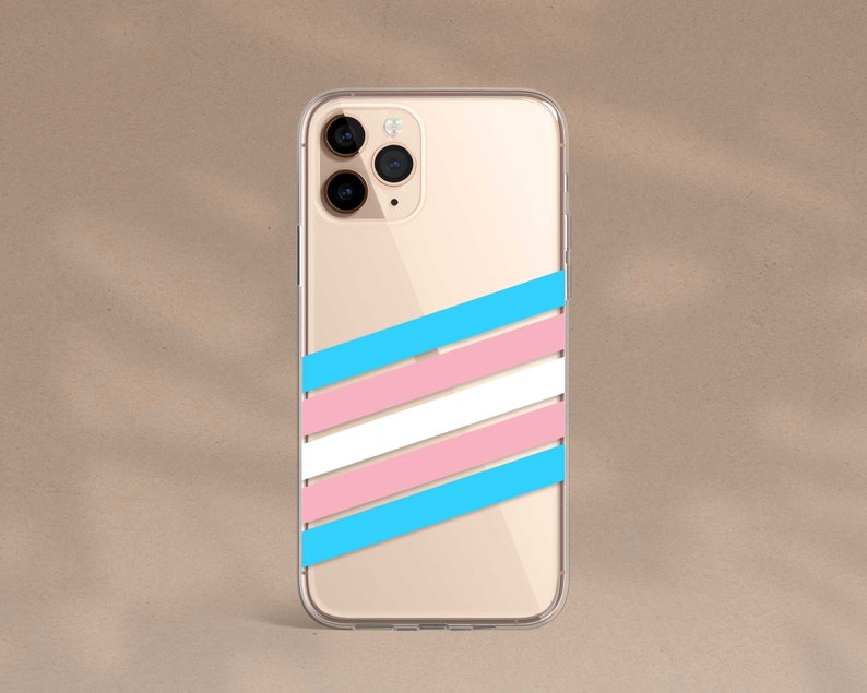 May include: A clear phone case with a gold background and a transgender pride flag design. The case has a camera cutout and a raised lip around the edges.