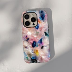 Op de afbeelding: Een kleurrijke telefoonhoes met een abstract roze, blauw en wit patroon. De hoes heeft een verhoogde camerabult met drie lenzen.