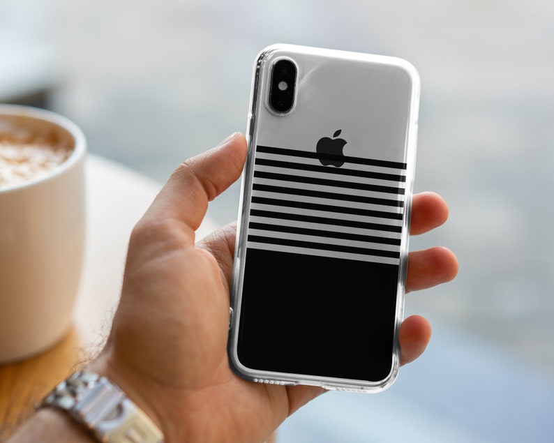 K&ouml;nnte beinhalten: Eine transparente Handyh&uuml;lle mit einem schwarz-wei&szlig;en Streifenmuster und einem schwarzen Apple-Logo. Die H&uuml;lle befindet sich auf einem schwarzen Hintergrund.