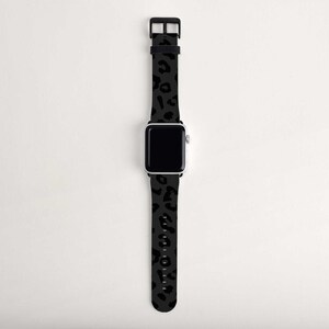 Puede incluir: Una banda de reloj Apple de leopardo negro y gris. La banda est&aacute; hecha de silicona y tiene una hebilla negra.