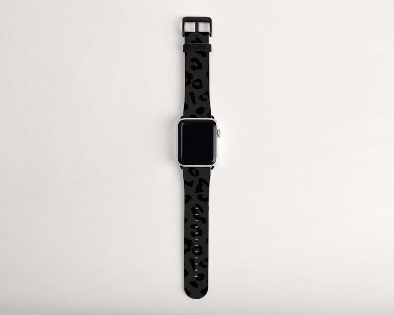 Puede incluir: Una banda de reloj Apple de leopardo negro y gris. La banda est&aacute; hecha de silicona y tiene una hebilla negra.