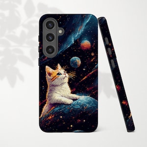 May include: A black phone case featuring a white and orange cat gazing upwards at a cosmic scene with planets and nebulae. The case is shown upright and leaning against a second case with a similar design.