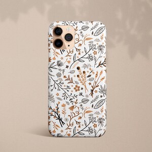 May include: White phone case with a floral pattern in brown and black. The phone case has a camera lens cutout.