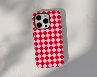 Puede incluir: Una funda de teléfono a cuadros rojos y rosados para un iPhone con una protuberancia de cámara.