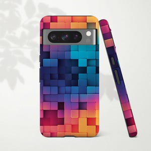 Puede incluir: Una funda para teléfono con un patrón geométrico colorido de cuadrados en tonos de azul, morado, rosa, naranja y amarillo. La funda tiene una protuberancia de cámara elevada y un recorte para el puerto de carga del teléfono.