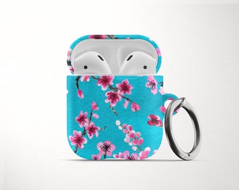 May include: A blue Airpods case with a floral pattern of pink cherry blossoms. The case has a silver ring attached to it.