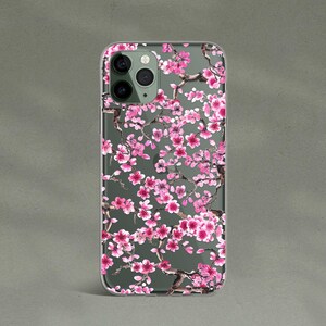 May include: A clear phone case with a pink and white floral design. The case features a pattern of cherry blossoms.