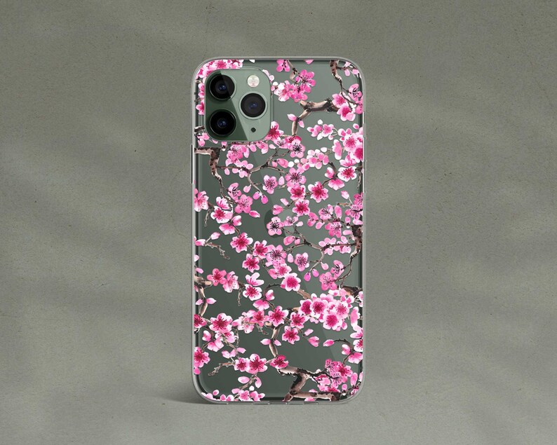 May include: A clear phone case with a pink and white floral design. The case features a pattern of cherry blossoms.