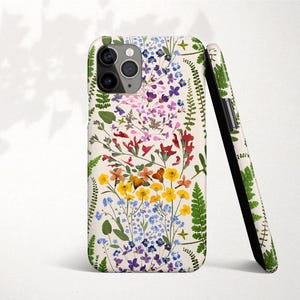 Op de afbeelding: Een witte iPhone-hoes met een bloemenpatroon met geperste bloemen in tinten roze, geel, blauw en groen. De hoes heeft een transparante camera-uitsparing en een witte achtergrond.