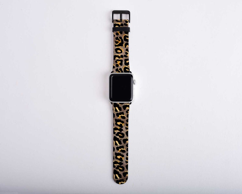 Puede incluir: Una correa de reloj de leopardo negro y dorado para un Apple Watch.