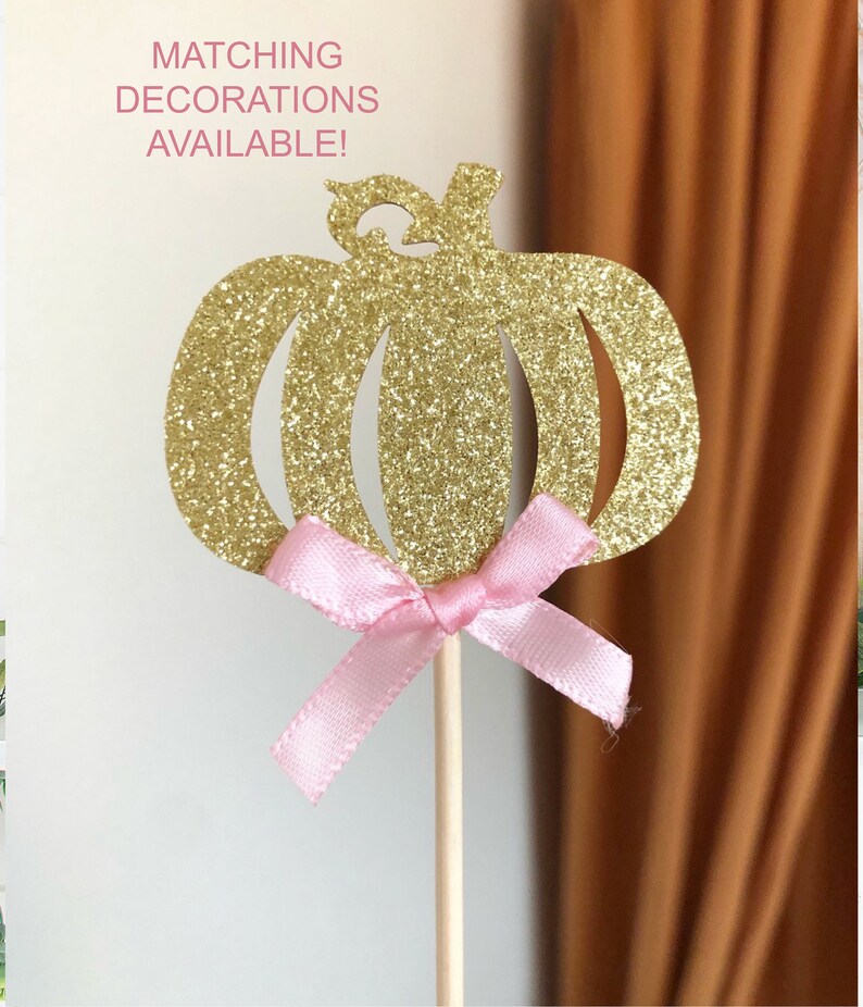 May include: Gold glitter pumpkin cake topper with a pink bow.  Matching decorations available.