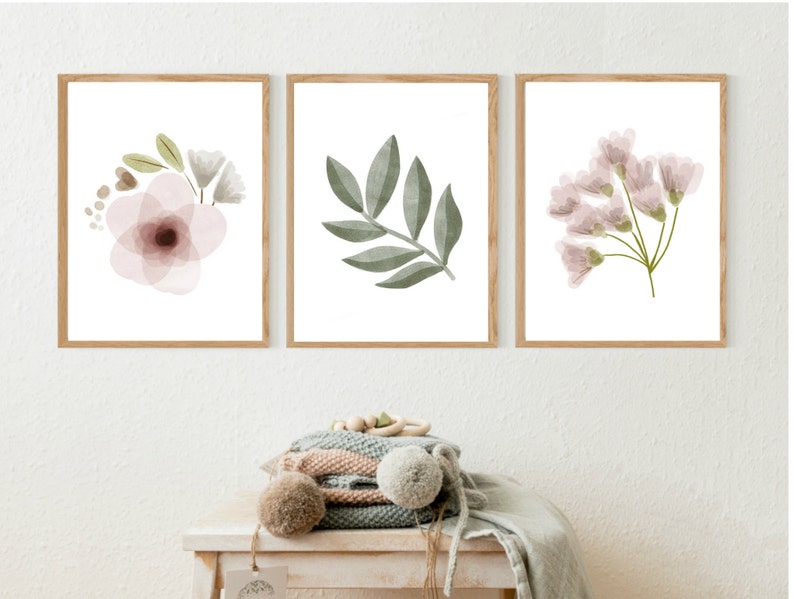 Pu&ograve; includere: Tre stampe ad acquerello incorniciate con motivi floreali e botanici. Le stampe presentano un fiore rosa, un ramo di foglie verdi e un gruppo di fiori rosa.
