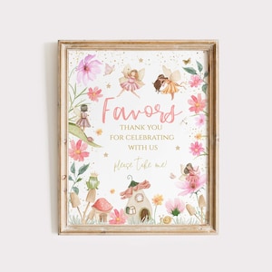 May include: A printable sign with a pink and gold fairy theme. The sign says "Favors" in pink script with gold glitter. The text below says "Thank you for celebrating with us. Please take one!" The sign is surrounded by watercolor illustrations of fairies, flowers, mushrooms, and a small house.