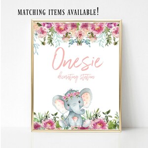 May include: A printable sign with a pink floral border and a gray elephant with a pink floral crown. The sign says "Onesies decorating station".