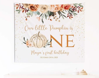 May include: A white banner with a watercolor pumpkin and floral design. The text reads "Our little Pumpkin is ONE Maya's first birthday OCTOBER 24th, 2021".
