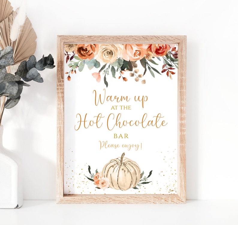 May include: A printable sign with a watercolor floral design in shades of orange, peach, and green. The sign says "Warm up at the Hot Chocolate Bar. Please enjoy!" and features a white pumpkin with gold accents.
