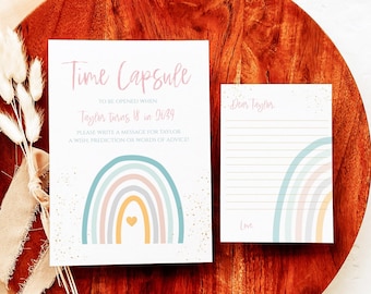 Peut inclure: Une carte blanche avec un motif arc-en-ciel et le texte "Time Capsule" et "To be opened when Taylor turns 18 in 2039". La carte comprend également le texte "Please write a message for Taylor, a wish, prediction or words of advice!" Une deuxième carte avec du papier ligné et le texte "Dear Taylor" et "Love" est également affichée.